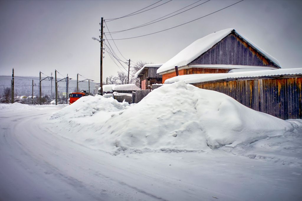 Снег с дороги снова сгребли к домам на Набережной. Фото: Вадим Аминов, «Вечерний Краснотурьинск»
